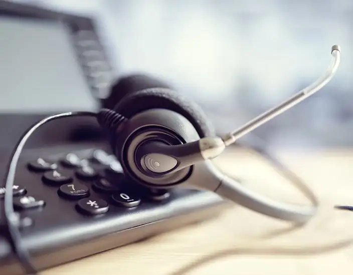 A headset resting on a desk phone